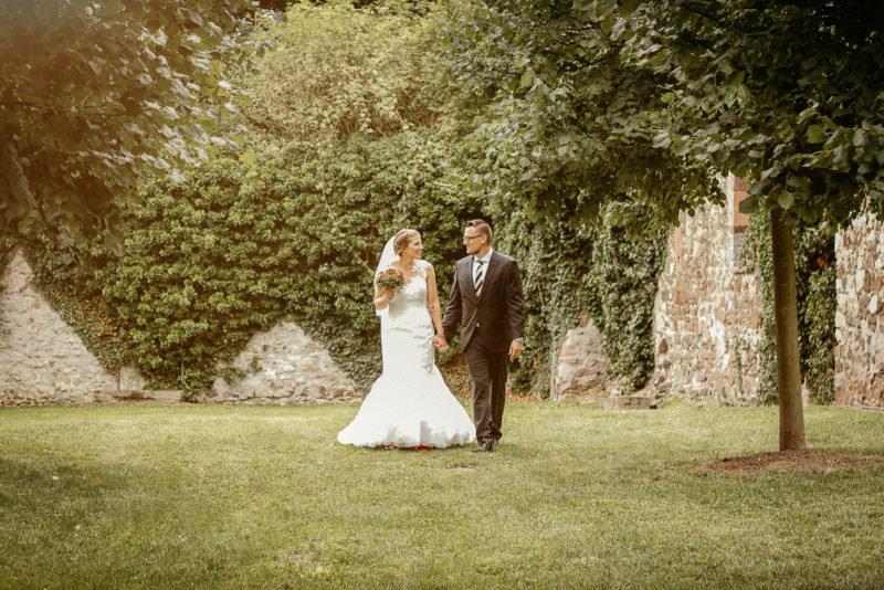 Brautpaar läuft auf einer Wiese.